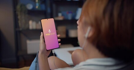 Young attractive Asia lady wear headphones using phone listen digital music podcast online channel sit on sofa in living room at house night. Social distancing, quarantine for coronavirus prevention. - Powered by Adobe