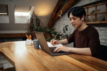 Asian man working at home. typing on computer.
