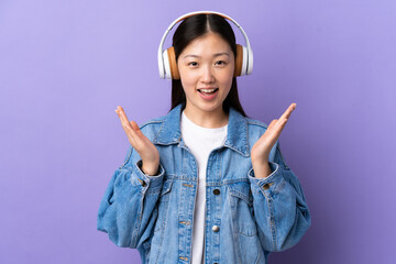 Young Chinese girl over isolated purple background surprised and listening music