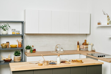 Interior of large modern kitchen with white cabinets, table and other stuff