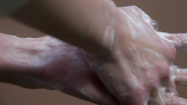 Female washing hands with soap on brown background