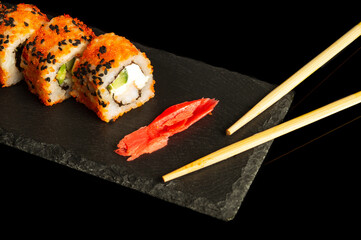 Traditional sushi and chopsticks. Philadelphia with salmon, avocado and cheese. Japanese cuisine on black background