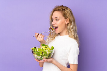 Young blonde woman holding salad isolated on purple background