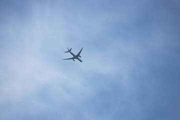Airplane flying in the blue sky on background of white clouds. Twin-engine commercial plane,...