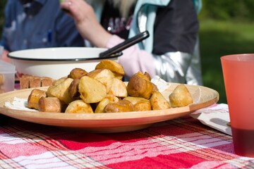 camping food. appetizing fried potatoes and sausages on table on blurred background. focus on foreground