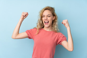 Fototapeta premium Young blonde woman isolated on blue background celebrating a victory