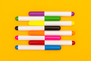 Multicolored markers on a yellow background. Photo for drawing with felt-tip pens.