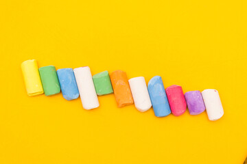 Children's drawing crayons lie in a row on a yellow background.
