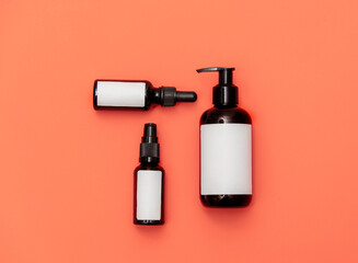 Three cosmetic bottles on pink background.