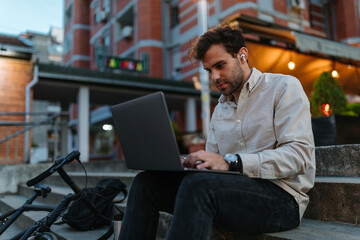 Handsome man using laptop outdoors