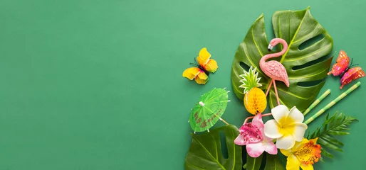 Gartenposter Exotic tropical summer background. Summer beach party concept. Pink flamingo, tropical leaves, orchid flowers and other accessories on green background. Flat lay, copy space. © Svetlana Kolpakova
