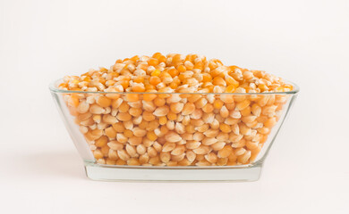 Dry corn in glass bowl on white background.