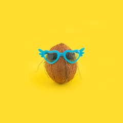 Summer concept with coconut with sunglasses on yellow background