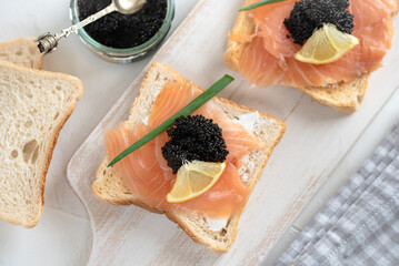 Appetizer toast bread with creamy cheese, salmon and black caviar.