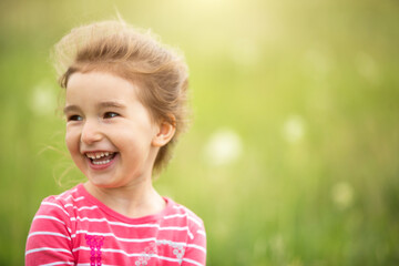 Portrait of a cute girl in field with a wild flower. Childhood, holidays in the country, freedom and carelessness. Summer time. International Children Day. Mosquito repellent, cottage core. Copy space