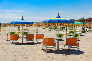 Bright, colorful umbrellas and sun loungers on the beach in Rimini, Italy.