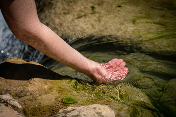 Hand of a Caucasian woman forms a cup and brings water from the clear stream of a river. Sentierelsa, Colle di Val d'Elsa, Siena - Tuscany, Italy