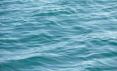 Fototapeta premium Texture of glitter water and soft waves. sparkling in water - background. sea water with sun glare and ripple. Powerful and peaceful nature concept.
