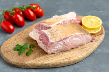 Fresh uncooked catfish with vegetables on wooden board.