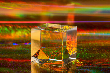Glass cube on abstract holographic background close up.