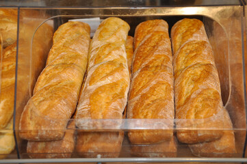 the freshly baked bread is ready for sale and lies in a plastic tray in the baking department of a grocery supermarket