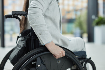 Obraz premium Close up of unrecognizable young businesswoman in wheelchair entering office building or school, copy space