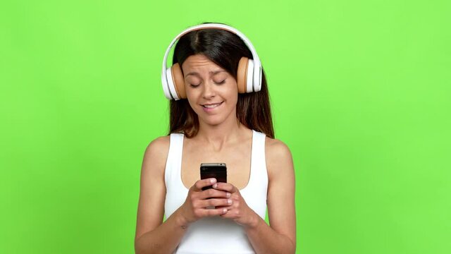 Young woman listening music with a mobile over isolated background