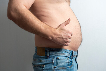 a fat man in jeans with a bare stomach and a finger raised in the air. The concept of body...