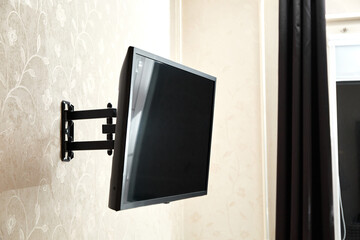 Swivel TV bracket LED display. Side view. X-shaped red fasteners. Black color. Multiplanar. Hangs on a wall. Reliable and comfortable fastening. Childproof and rollover protection. Metallic equipment