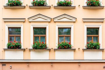 Fototapeta na wymiar Facade of an old European house with windows and decorated with flowers