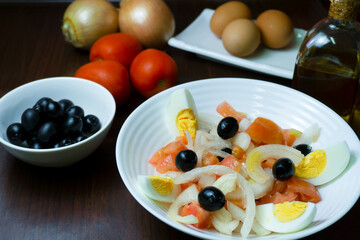 Plato de ensalada saludable, con tomate, cebolla,huevo y aceitunas negras.