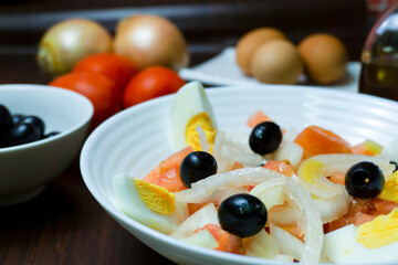 Plato de ensalada saludable, con tomate, cebolla,huevo y aceitunas negras.