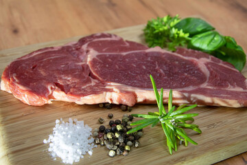 Raw entrecote steak with salt, pepper, basil, parsley and rosemary