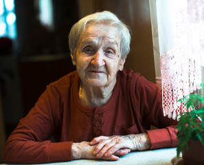An old senior woman sitting at the table.