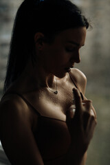 A silhouette of a brunette girl who stands at the window in her lingerie and sprinkles perfume on herself - 434000787