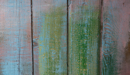 Old boards with cracked paint, peeling and cracks, randomly painted in delicate colors: pink, yellow, blue, green.