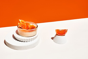 Creme brulee french dessert with caramelized brown cane sugar orange background. Two portion of delicious catalan cream. Creative food with podium. Copy space. Selective focus.