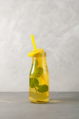 Refreshing summer drink. Mojito cocktail with lemon, lime and mint in yellow glass bottle. Grey background, copy space
