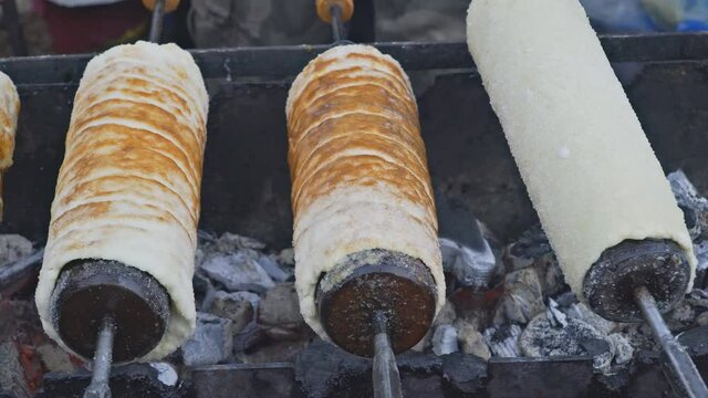 Czech traditional sweet pastry over wrapped around Trdelnik pastry bun, cooked on fire metal stick and baked with cinnamon sugar European dessert.