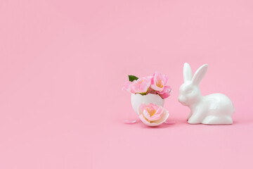Sakura flowers in eggshell and porcelain bunny on pink back. Minimal creative Easter concept. Festive card. Selective focus, place for text.