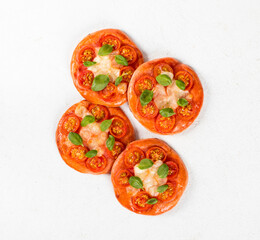 Children mini pizza pink with with beet juice added to the dough, tomatoes, mozzarella and basil on a white background top view