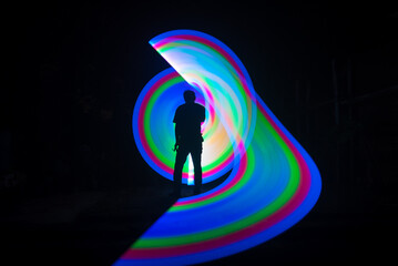 One person standing alone against beautiful color circle LED light painting as the backdrop