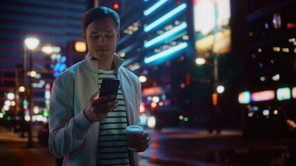 Portrait of Man Using Smartphone, Drinking Beverage, Walking Through Night City Street Full of Neon Light. Smiling Stylish Man Using Mobile Phone, Social Media, Online Shopping, Texting on Dating App - Powered by Adobe