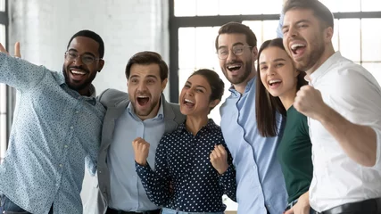 Foto op Canvas Multiethnic team of excited employees celebrating corporate achievement, high sales result, work success, shouting for joy. Happy diverse professionals hugging, laughing, making winner gestures © fizkes
