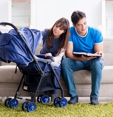 Young parents with their newborn baby in baby pram sitting on th