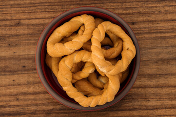 Pieces of traditional Latin American pastry called ROSQUITAS DE SAL or ROSCAS made with wheat flour. Top view of Neapolitan cookies called TARALLI. Stale salt bagels. Wood table. Ecuador