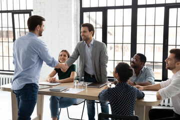 Happy millennial business team welcoming new employee, HR manager getting acquainted with...