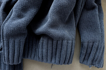 bottom part of an old navy blue zipper down sweater - photographed from above with low or raking light - emphasis on texture and folds