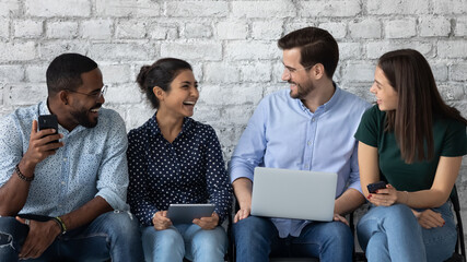 Happy diverse job candidates chatting and laughing waiting for interview in queue. Multiethnic...
