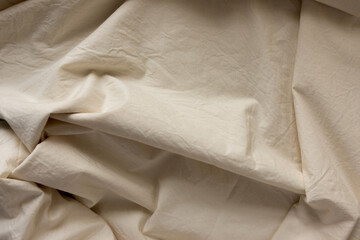 warm ivory yellow cotton blend fabric - photographed from above with low or raking light - emphasis on texture and folds